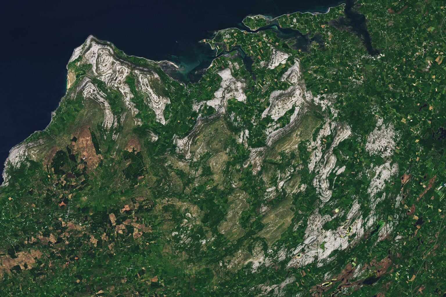 A Bit of Gray on an Emerald Isle A satellite view of the Burren in western Ireland shows gray limestone hills arranged in curved, concentric bands surrounded by green farmland and small towns.