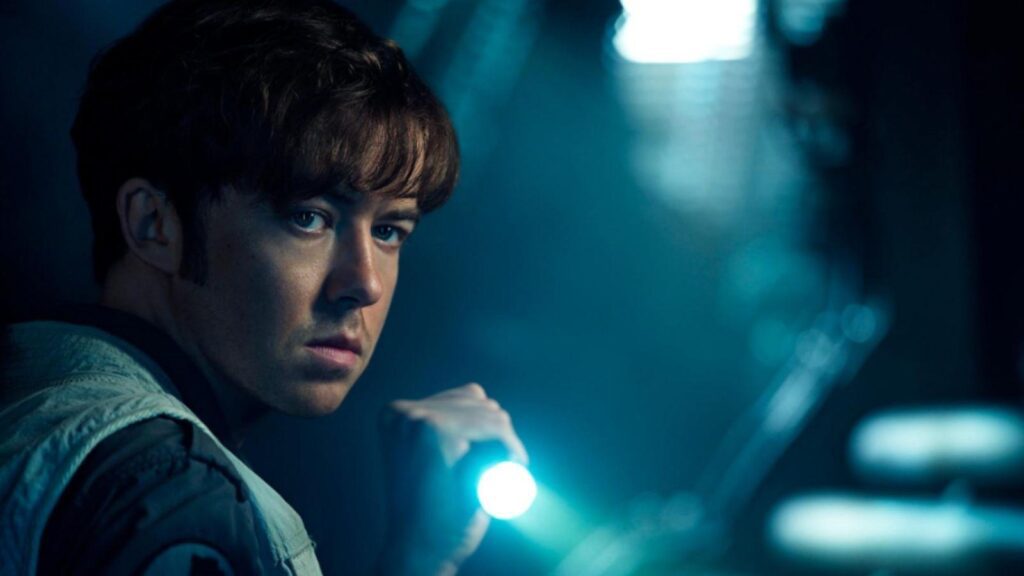 Samuel Blenkin holding flashlight in dark corridor looking alert Alien Earth, from Alien: Earth season 1
