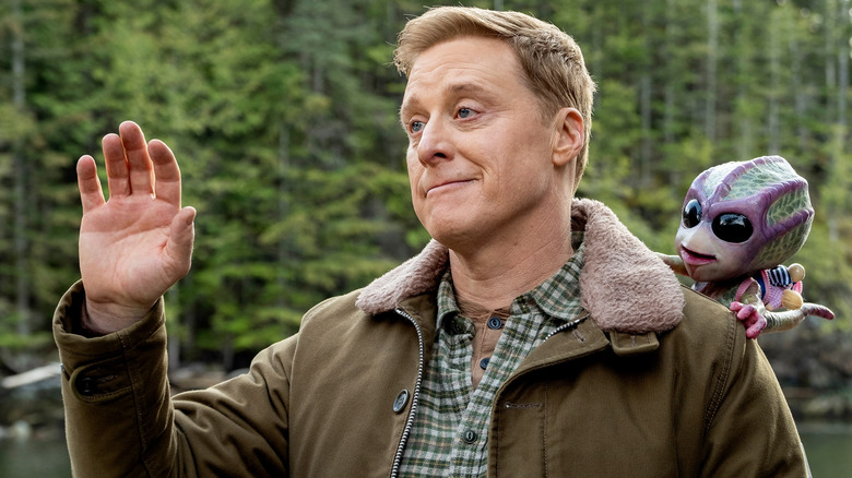 Harry waving with a small alien on his shoulder in 