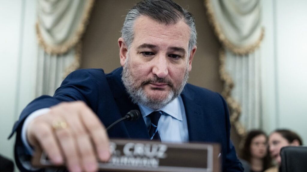 The US Senate empowers NASA to fully engage in lunar space race Senator Ted Cruz at a Senate committee hearing, sitting in his seat and using his hand to move a nameplate that says "Mr. Cruz, Chairman."