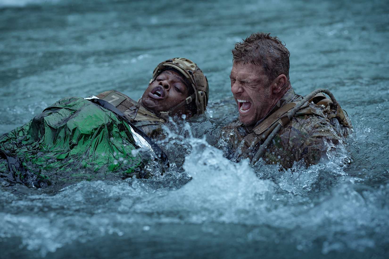 Army sergeant 81 (Alan Ritchson) screams as he swims across a raging river, dragging a wounded fellow soldier, in War Machine
