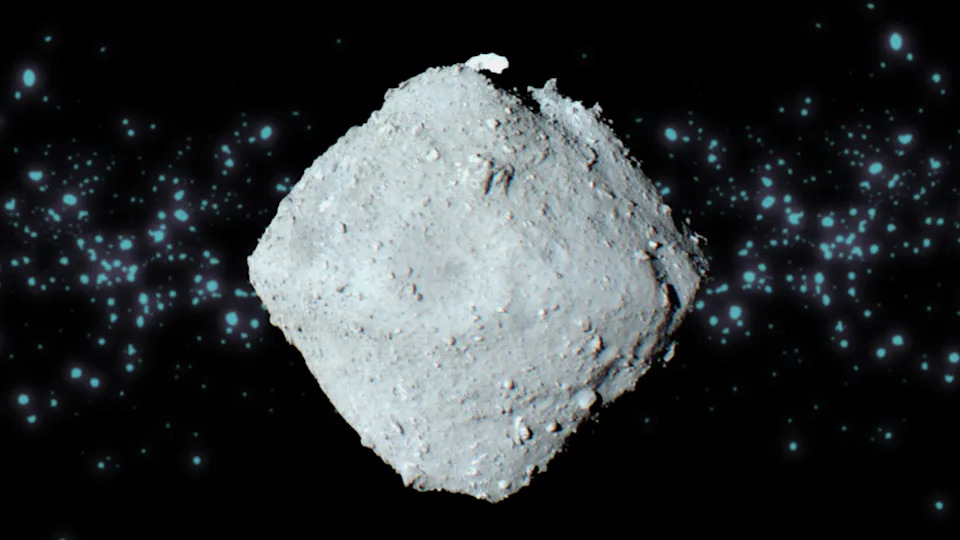  A gray top-shaped space rock with a swarm of light blue dots behind it. 