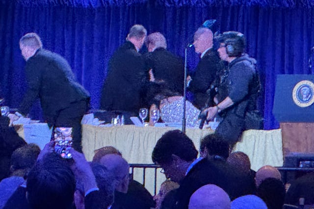 Donald Trump is escorted off a stage by numerous Secret Service agents