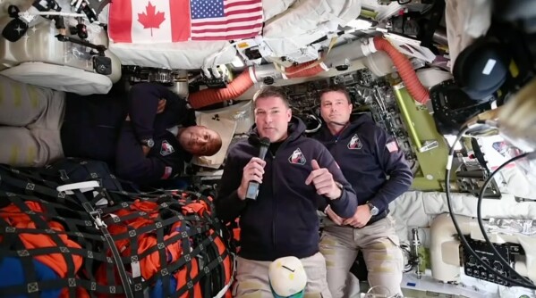 This image provided by the Canadian Space Agency, Artemis II astronaut Jeremy Hansen of Canada, connects live from the Orion spacecraft and speaks with Canadian media along with astronauts Victor Glover, left, and Reid Wiseman on Saturday, April 4, 2026. (Canadian Space Agency via AP)