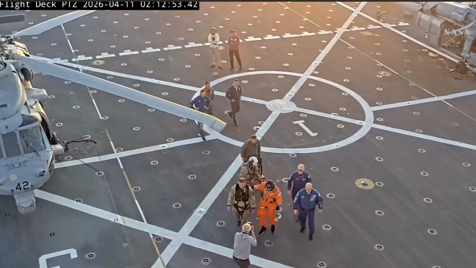 Commander Reid Wiseman crossing the flight deck with the Artemis II's mascot Rise in his hand. Rise has returned to Earth!