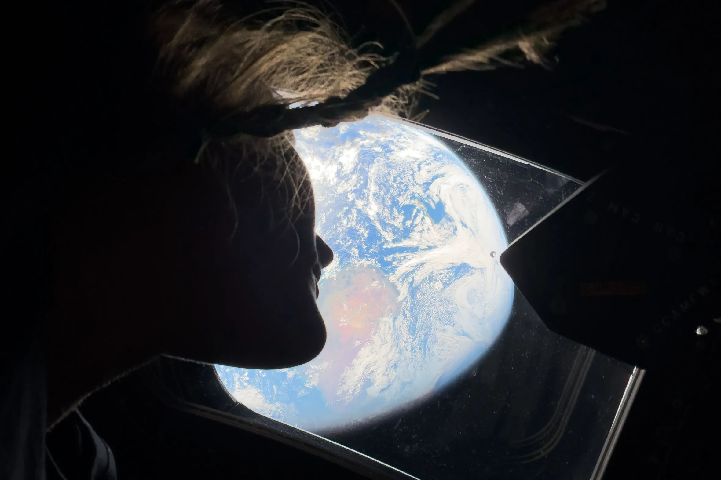 Astronaut Christina Koch looking out of the Orion spacecraft window at Earth.
