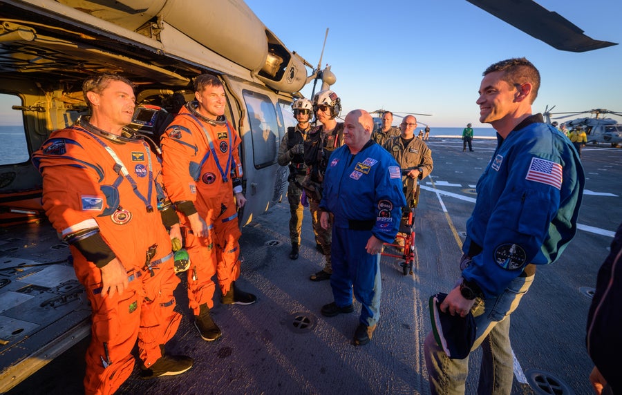 Artemis II astronauts Reid Wiseman and Jeremy Hansen converse with NASA Administrator Jared Isaacman and other personnel aboard the U.S.S. John P. Murtha after a successful splashdown and recovery.