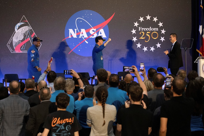 A NASA press conference with people and astronauts. 