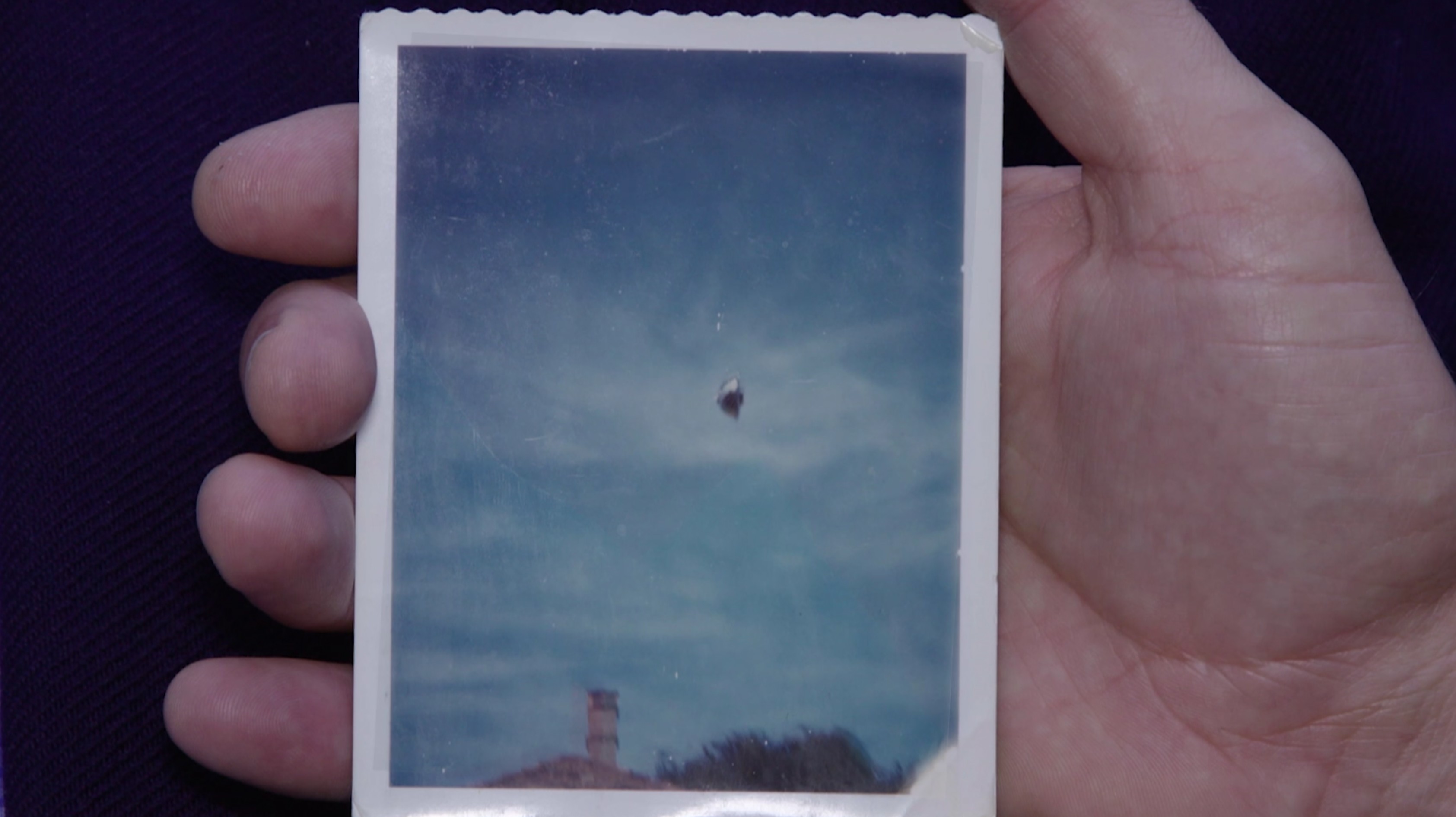 A photo of an object in a blue sky in the palm of a person's right hand