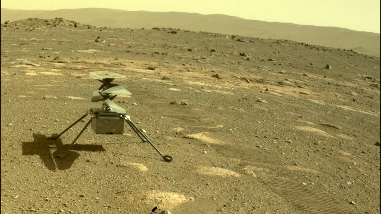 a small helicopter sits in red rocky dirt