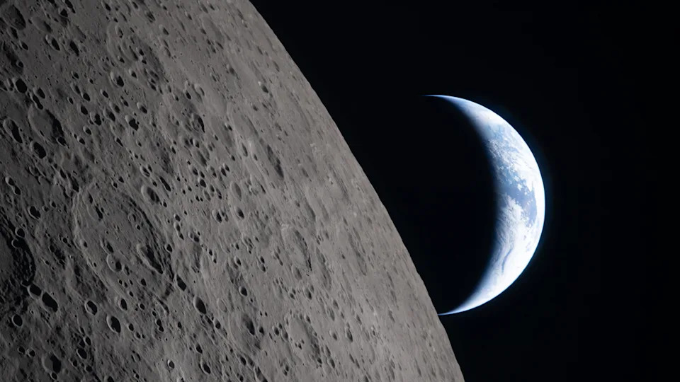 A view of Earth from the moon, with half the Earth illuminated and the gray surface of the moon in the foreground.