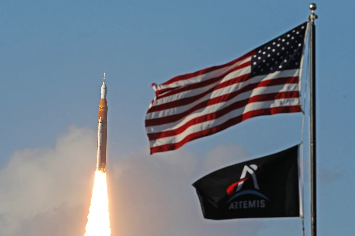 The Artemis II crewed lunar mission launches in front of the American flag.