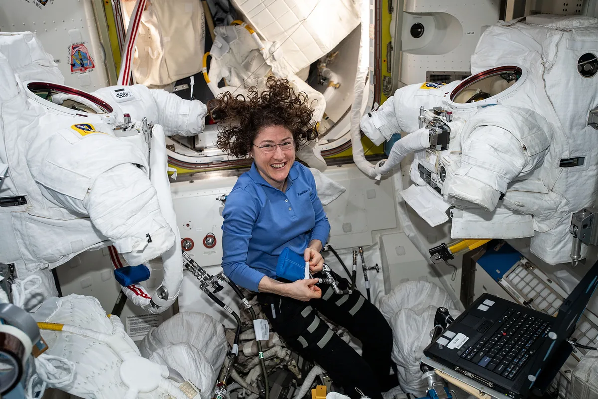 Christina Koch in the ISS preparing spacesuits before a space walk
