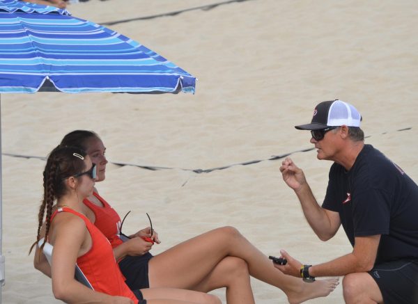 Head Coach Karl Seiler kneels in front of duo partners Emma Bambe (#12) and Reese Maffitt (#13) to speak to them during their match on March 27 at MiraCosta college.