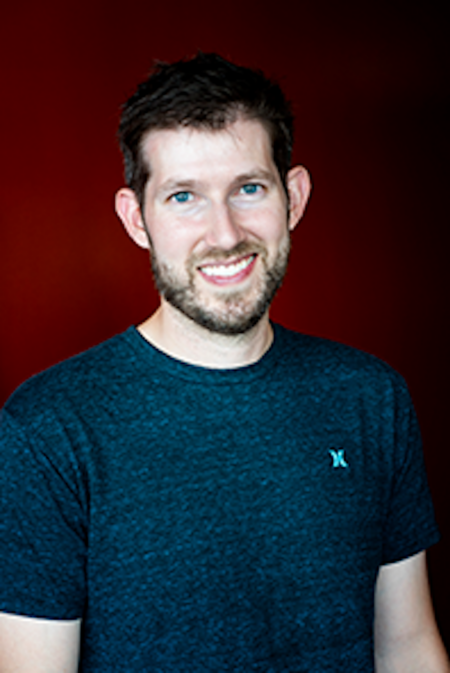 Smiling man wearing a dark blue t-shirt with a small X logo on it.