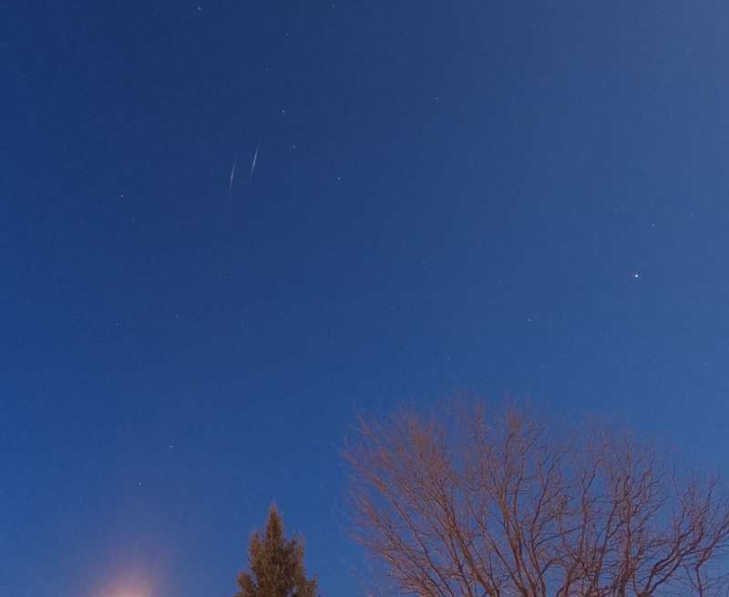 Dark blue sky with two parallel streaks of Lyrid meteors in the sky.
