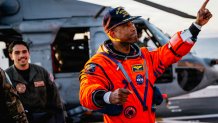 NASA astronaut Victor Glover points at crew members on the flight deck of the San Antonio Class amphibious transport dock USS John P. Murtha (LPD 26) after returning from space on Apr. 10, 2026. John P. Murtha is underway in the U.S. 3rd Fleet area of operations supporting NASA’s Artemis II mission, retrieving the crew and spacecraft following their return to Earth and splashdown in the Pacific Ocean. NASA’s Artemis II mission sent four astronauts on a flight around the moon in the Orion space craft, ma