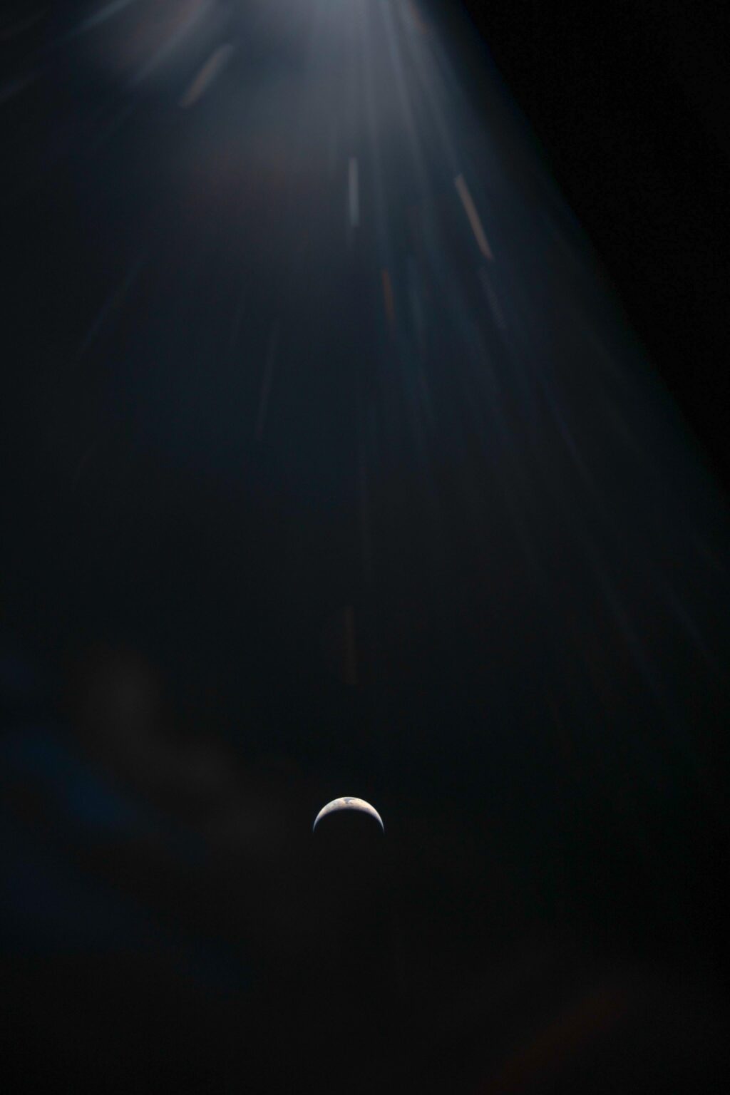 A Crescent Earth against the blackness of space is seen through the window of the Orion spacecraft.