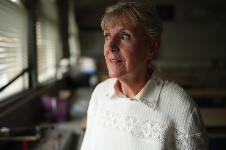 Woman in her 60s with short grey hair looks out a window
