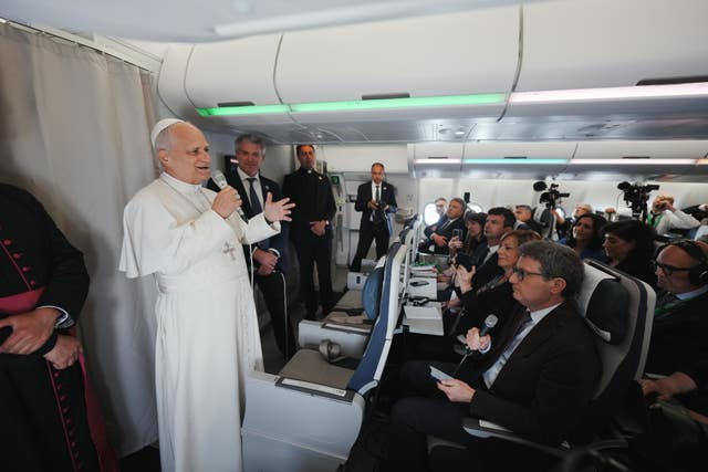 Pope Leo XIV speaking into a microphone to journalists aboard the papal flight