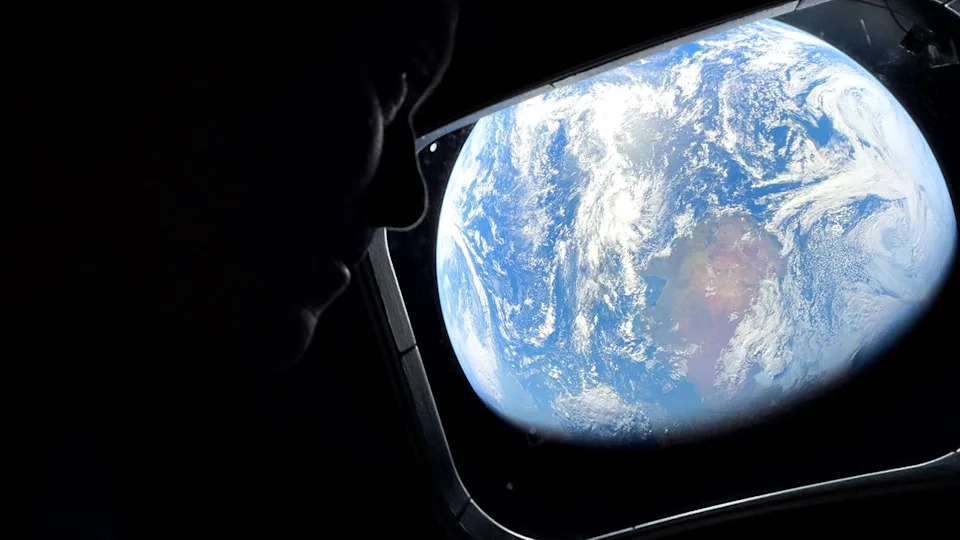 Astronaut Reid Wiseman looking out Orion spacecraft window at Earth.