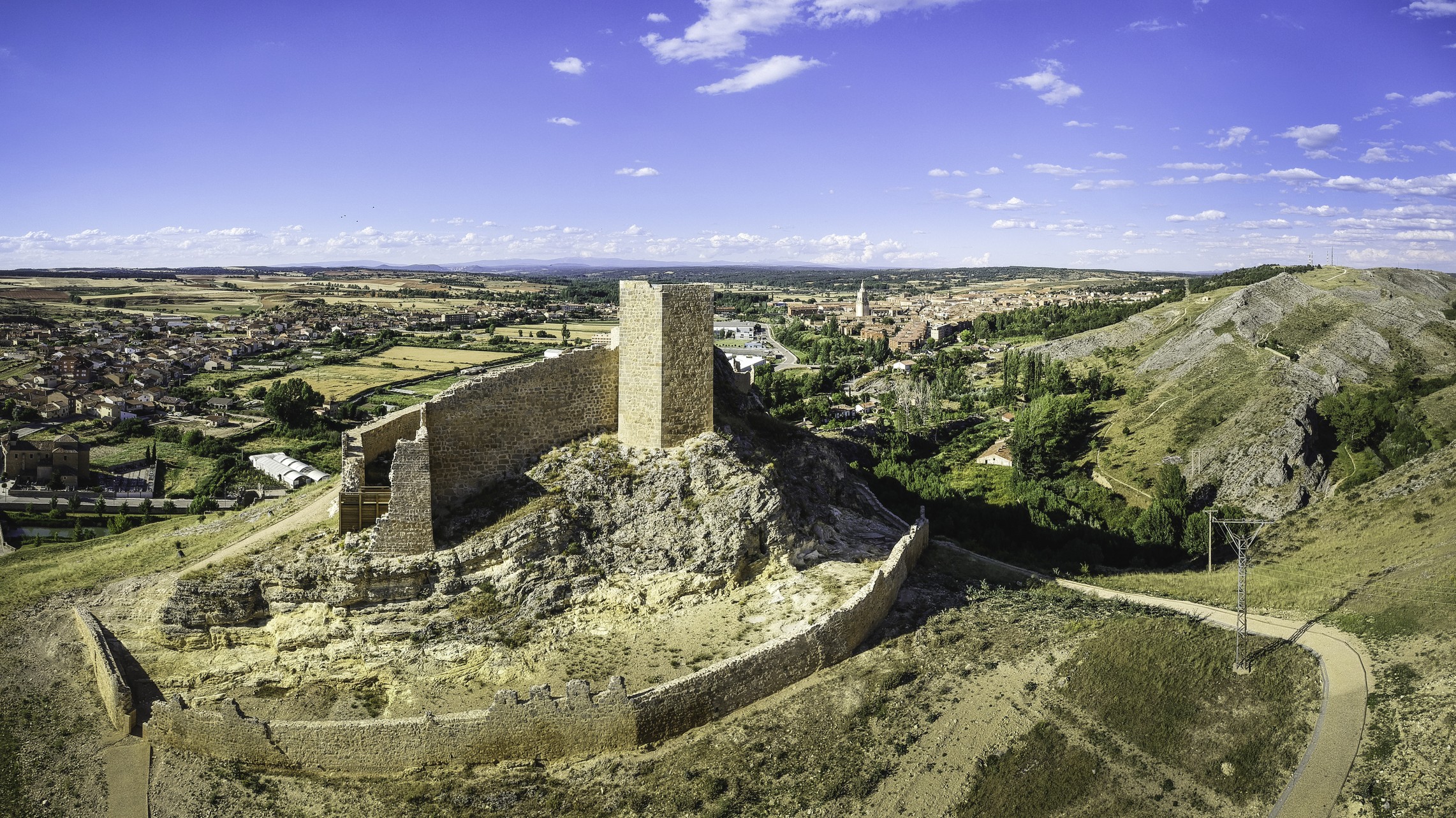 a small castle in ruins atop a hill.