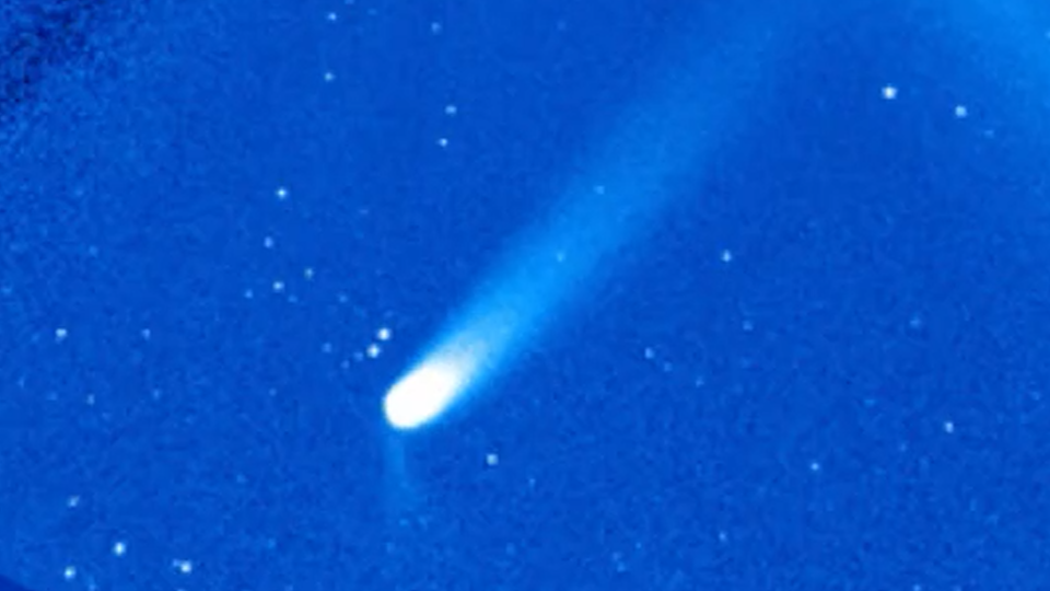 A comet is pictured in a coronagraph with a large sweeping tail extendin to the upper right of the screen.