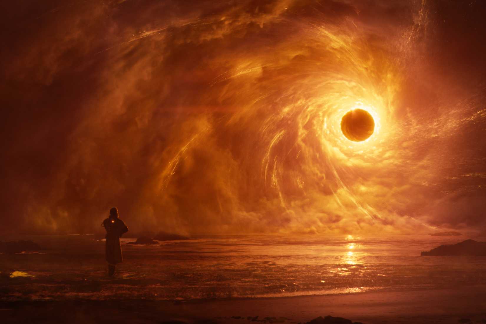 A lone soldier stands before a massive swirling vortex over an alien ocean