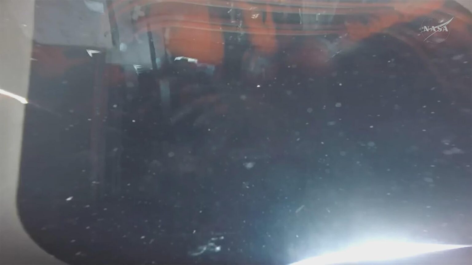 View from inside the Orion capsule "Integrity", looking out one of the windows. The Sun can be seen coming up over Earth's horizon at lower right.
