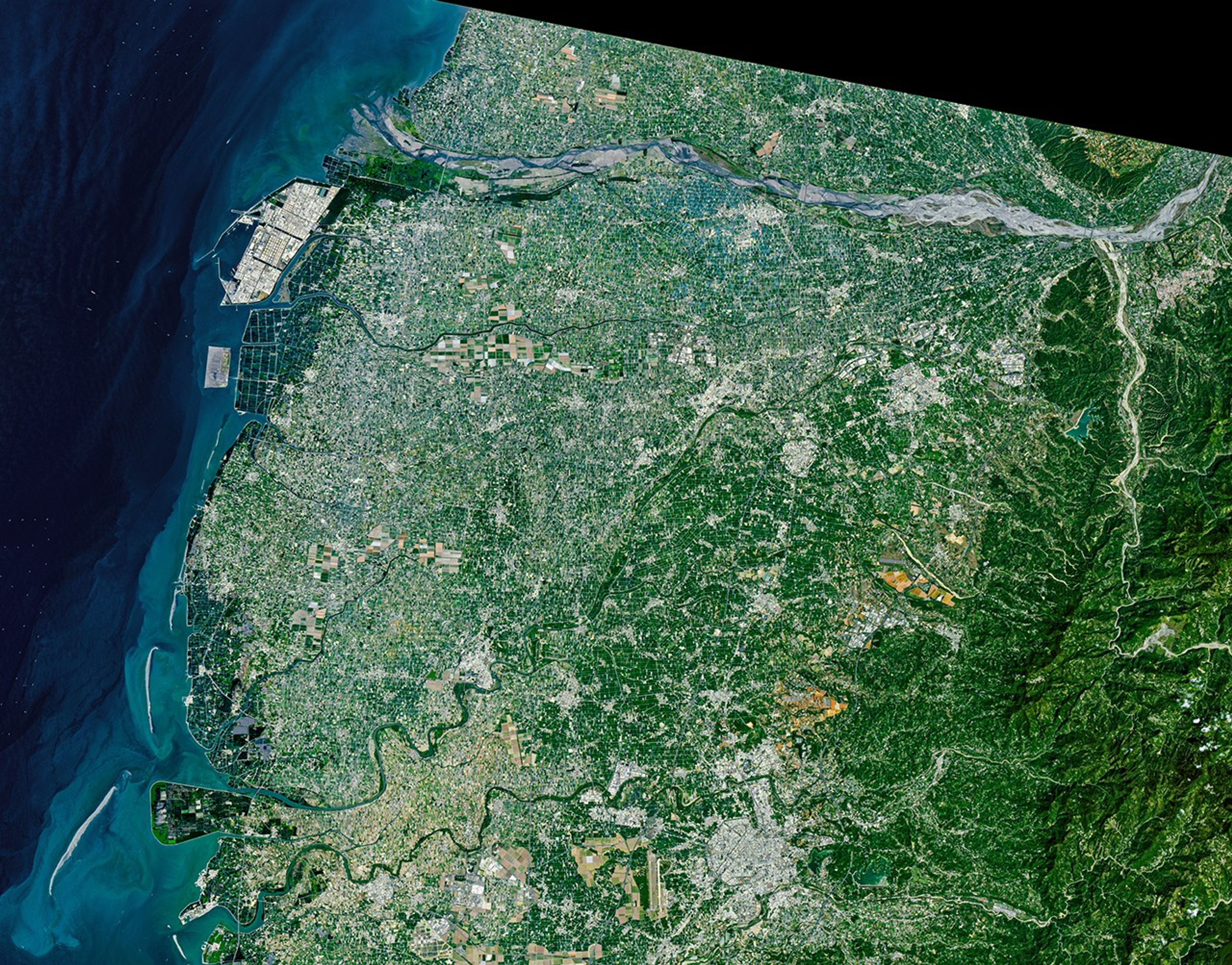 An array of green rectangular parcels of farmland in a range of hues is interspersed with several small towns.