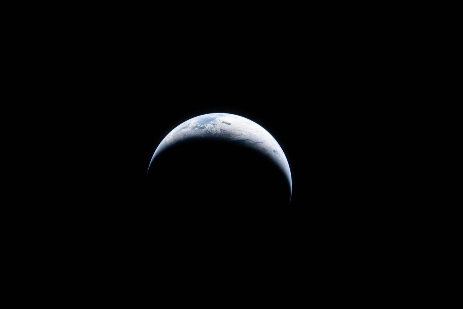 Earth is illuminated against the blackness of space.