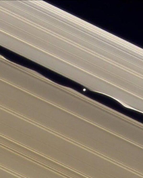 A small moon of Saturn creating massive waves in the planet's rings.