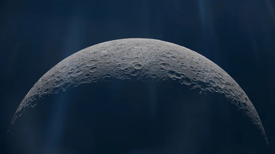 A close up of the moon's surface, showing its top half illuminated by glowing light from above. 