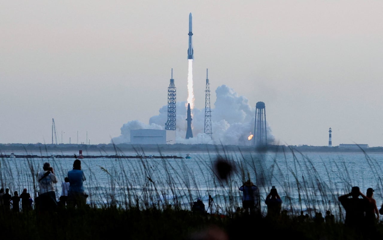 A white rocket leaves a plume of vapour as it soars into a blue sky.