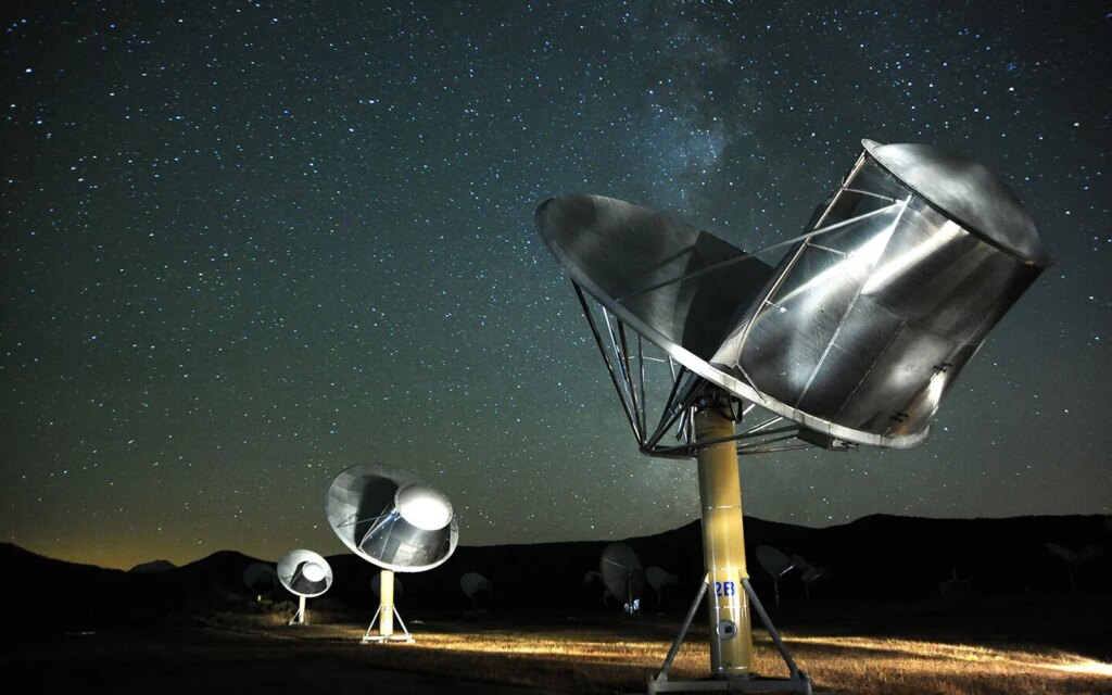Telescopes of the Allen Telescope Array sit beneath a starry night sky. The array is designed to listen for signals sent or generated by extraterrestrial life.
