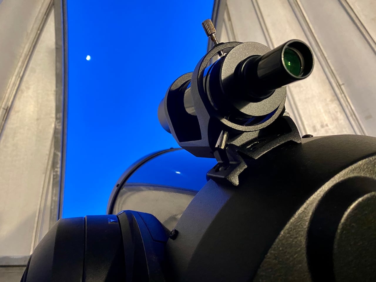 A  picture of a observatory, the telescope is peaking out of the building, looking into the night sky.