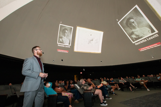 a massive presentation on a planetarium screen with an audience below