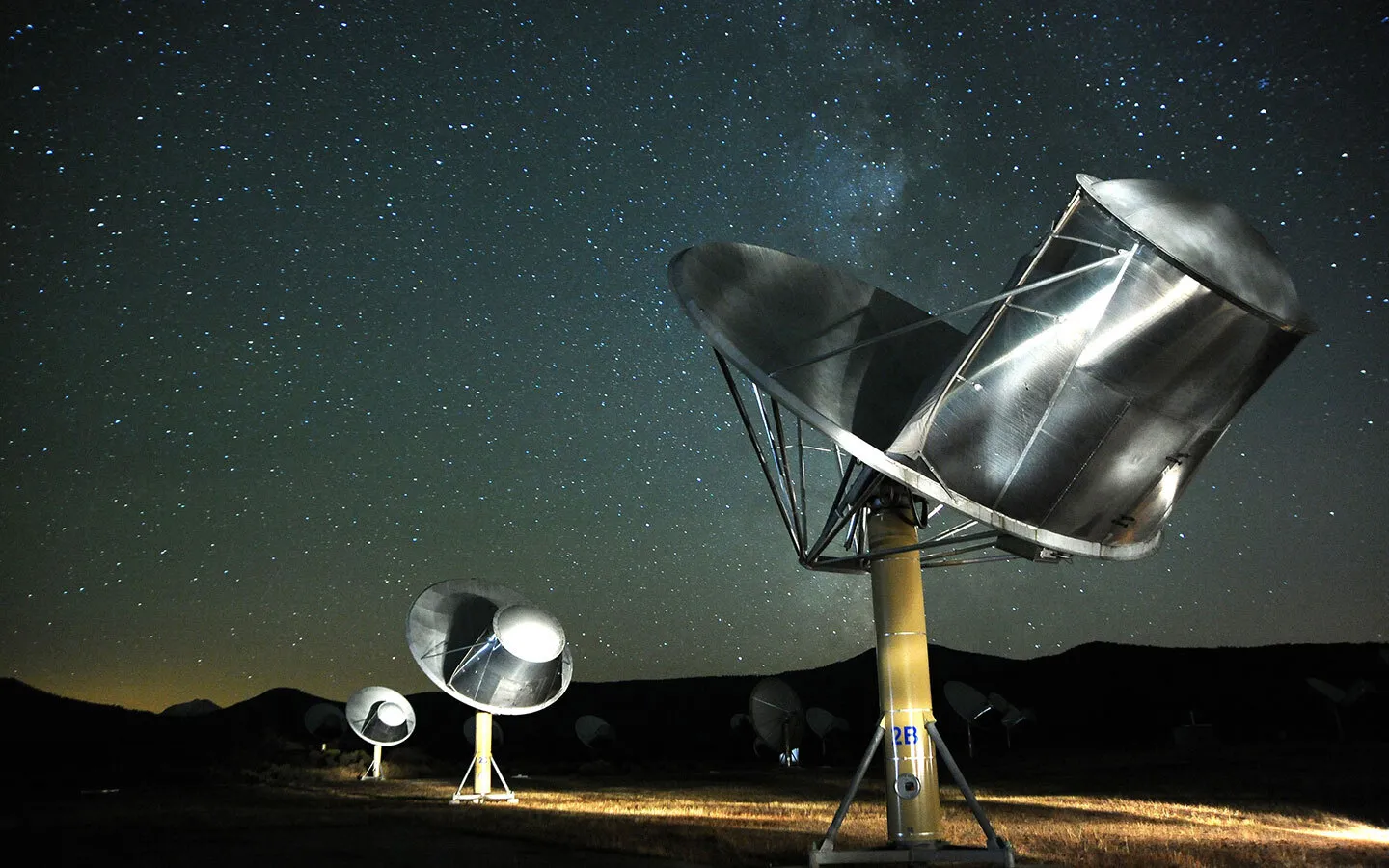 Telescopes of the Allen Telescope Array sit beneath a starry night sky. The array is designed to listen for signals sent or generated by extraterrestrial life.