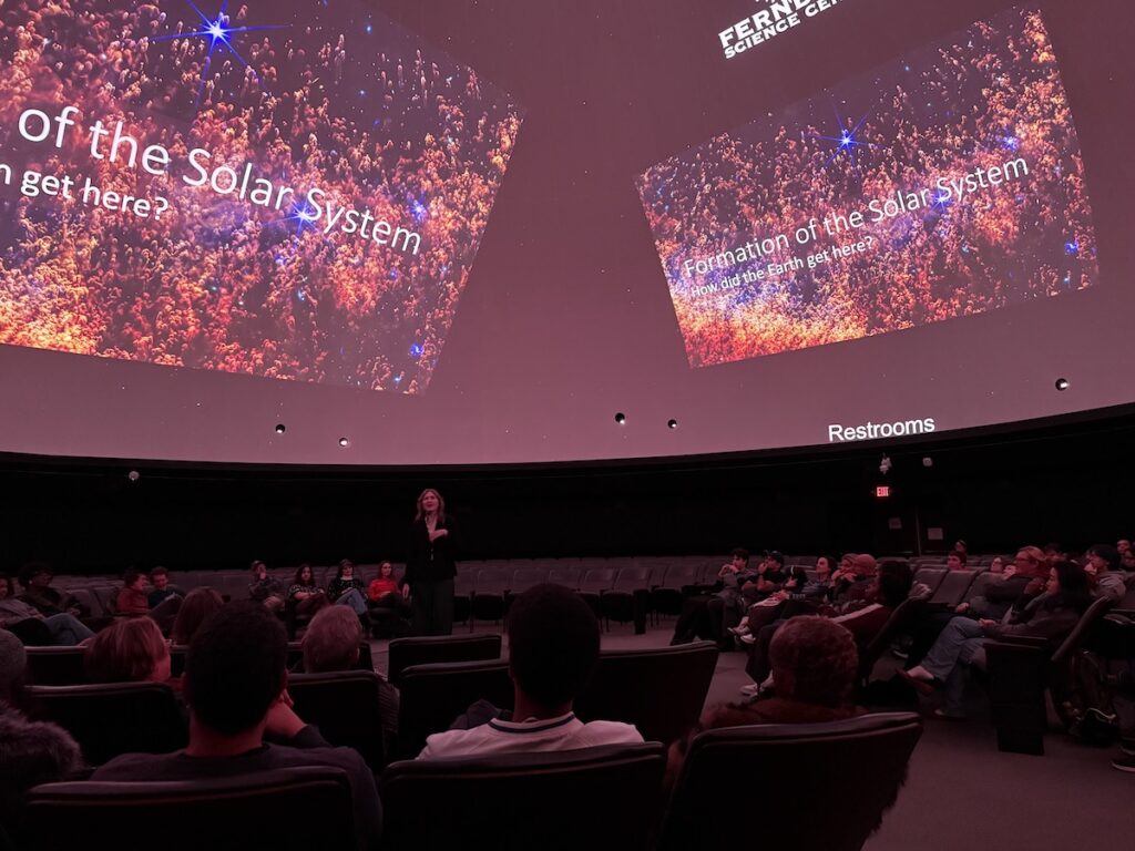 a massive presentation on a planetarium screen with an audience below