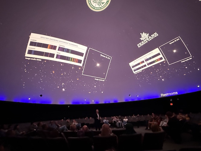 a massive presentation on a planetarium screen with an audience below