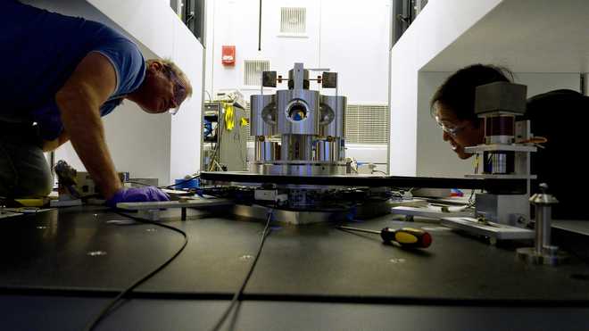 Scientists Stephan Schlamminger (left) and Vincent Lee examine the torsion balance they used to measure the gravitational constant, Big G.