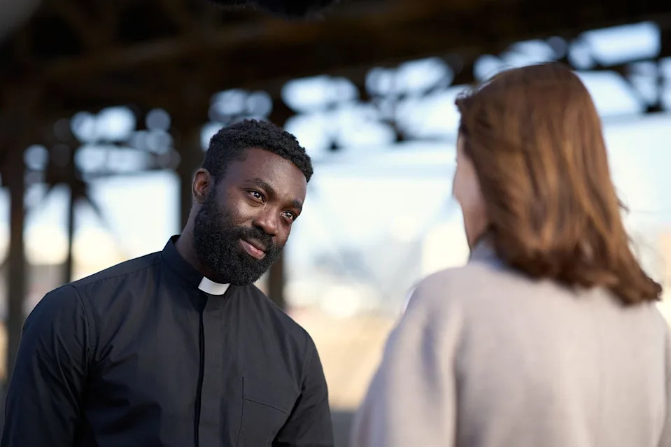 clergy member speaking with a woman in a casual setting