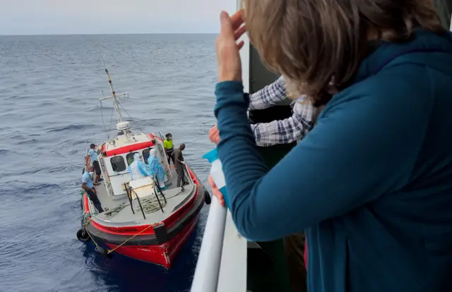 Passengers on the hantavirus-stricken cruise ship, MV Hondius, watch epidemiologists board the boat