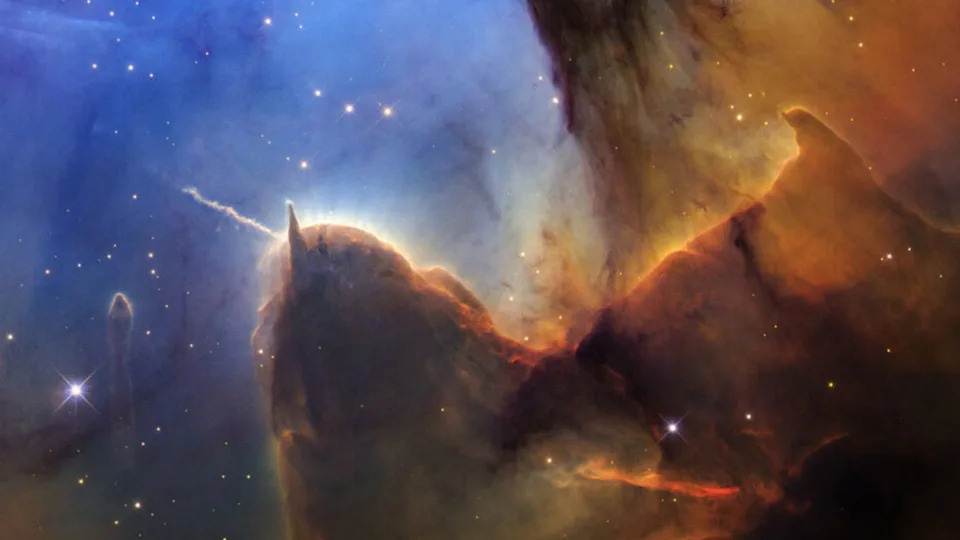 Glowing shapes of brown gas and dust swirl against a dark blue starry background