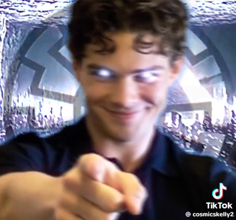Smiling man with glowing eyes points at the camera.