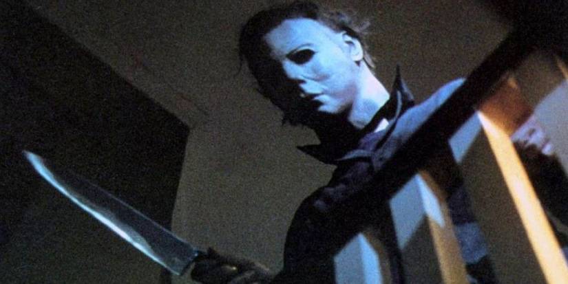 Michael Myers holds a knife and looks over the bannister of a staircase in Halloween (1978).