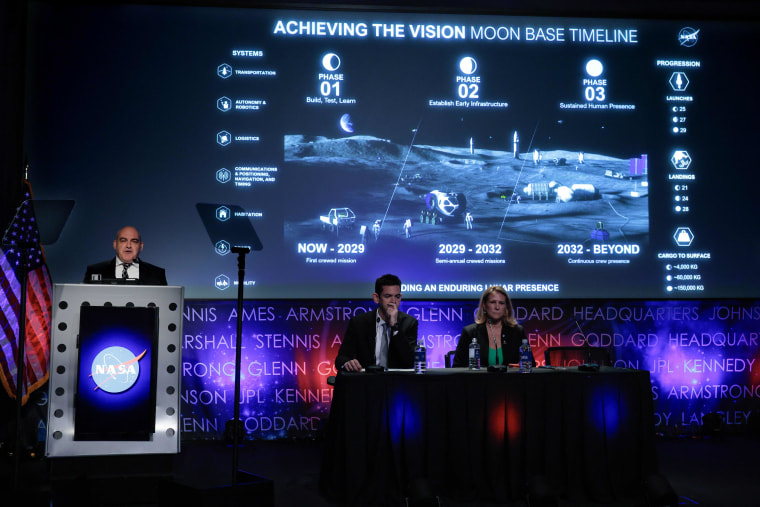 Moon Base Program Executive Carlos Garcia-Galan (L) gives a presentation about plans to establish a permanent presence on the lunar surface during a news conference with Administrator Jared Isaacman (2nd L) and Exploration Systems Development Mission Directorate acting Associate Administrator Lori Glaze at NASA headquarters on May 26, 2026 in Washington, DC.