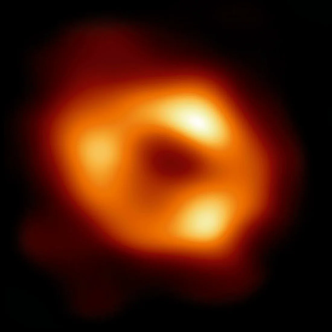 This image shows Sagittarius A*, the supermassive black hole at the centre of the Milky Way, captured using 2017 Event Horizon Telescope (EHT) observations. The black hole itself is completely dark, surrounded by a ring of glowing gas warped by its gravity