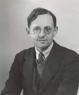 Portrait of a man wearing glasses and a suit, looking confidently at the camera. Frank Hawking, father of Stephen Hawking.