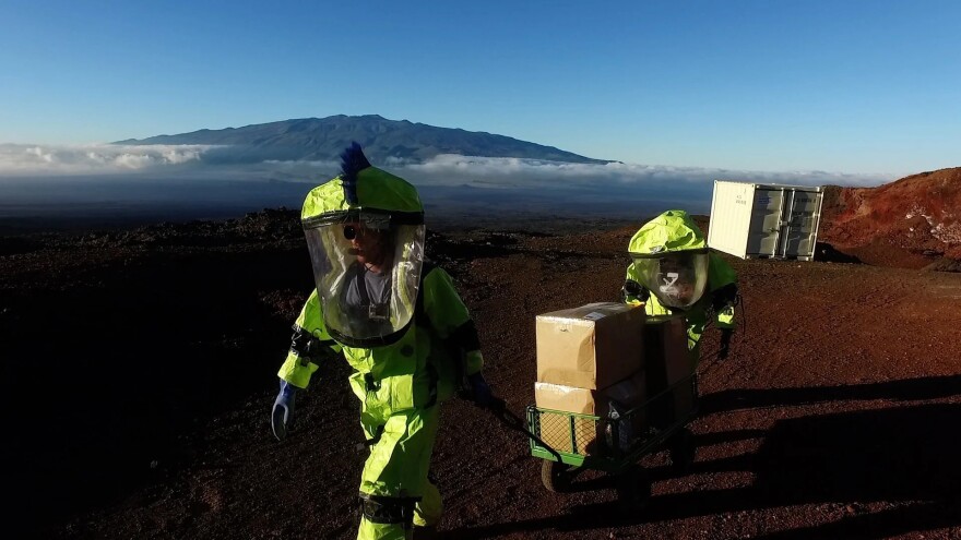 HI-SEAS crewmembers carry a cart up the slopes of Maunaloa volcano.